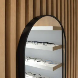Wystawa okularów w metalowej ramie na tle drewnianej ściany z pionowymi panelami.