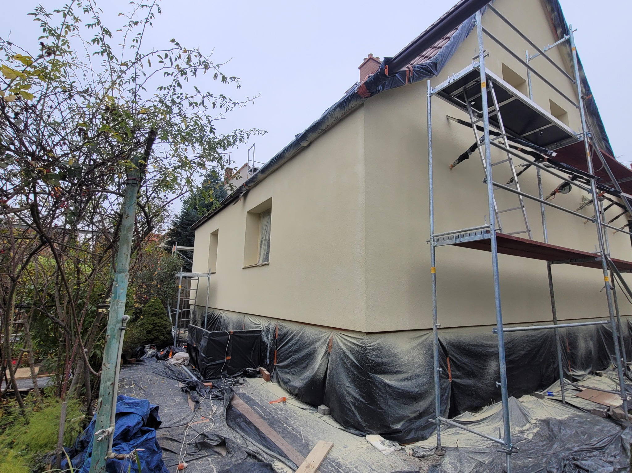 Elewacja budynku w trakcie ocieplania we Wrocławiu, widoczne rusztowania i zabezpieczenia folią.