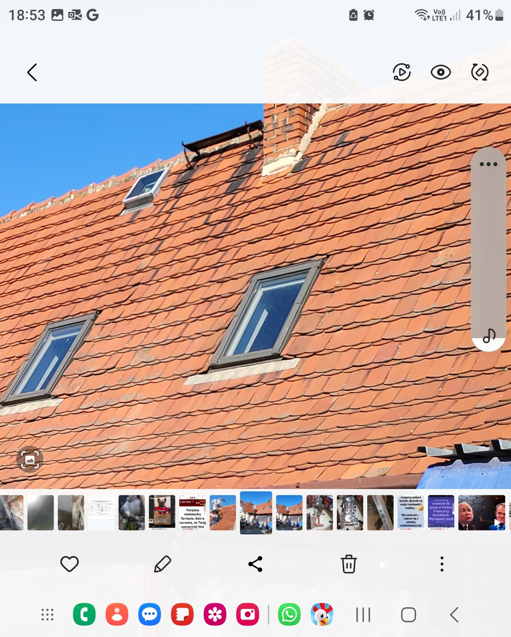 Czerwona dachówka z trzema oknami dachowymi i ceglanym kominem na tle błękitnego nieba. Widoczne ślady użytkowania na dachówkach.
