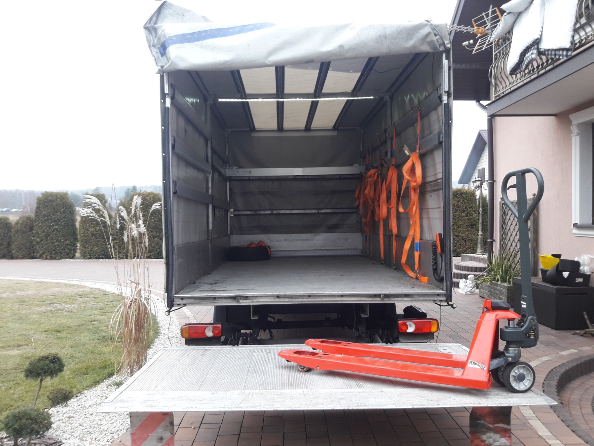 Otwarta paka samochodu dostawczego z rampą załadowczą i wózkiem paletowym w Smykowie, gotowa do załadunku towarów.