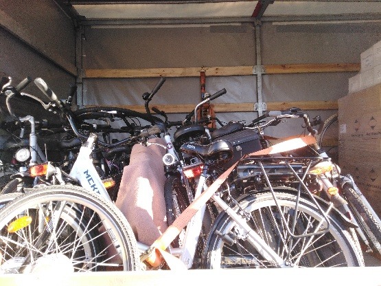 Wnętrze furgonetki załadowane rowerami różnego typu, zabezpieczonymi pasami transportowymi, gotowymi do przewozu.