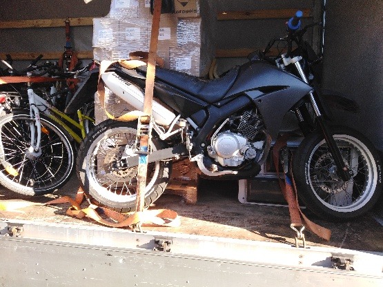 Motocykl i rower zabezpieczone pasami transportowymi wewnątrz przestrzeni ładunkowej pojazdu.