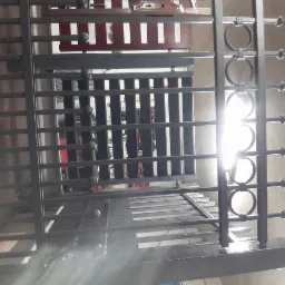 Metalowa konstrukcja z elementami dekoracyjnymi w postaci kół, widok z dołu, oświetlona silnym światłem.