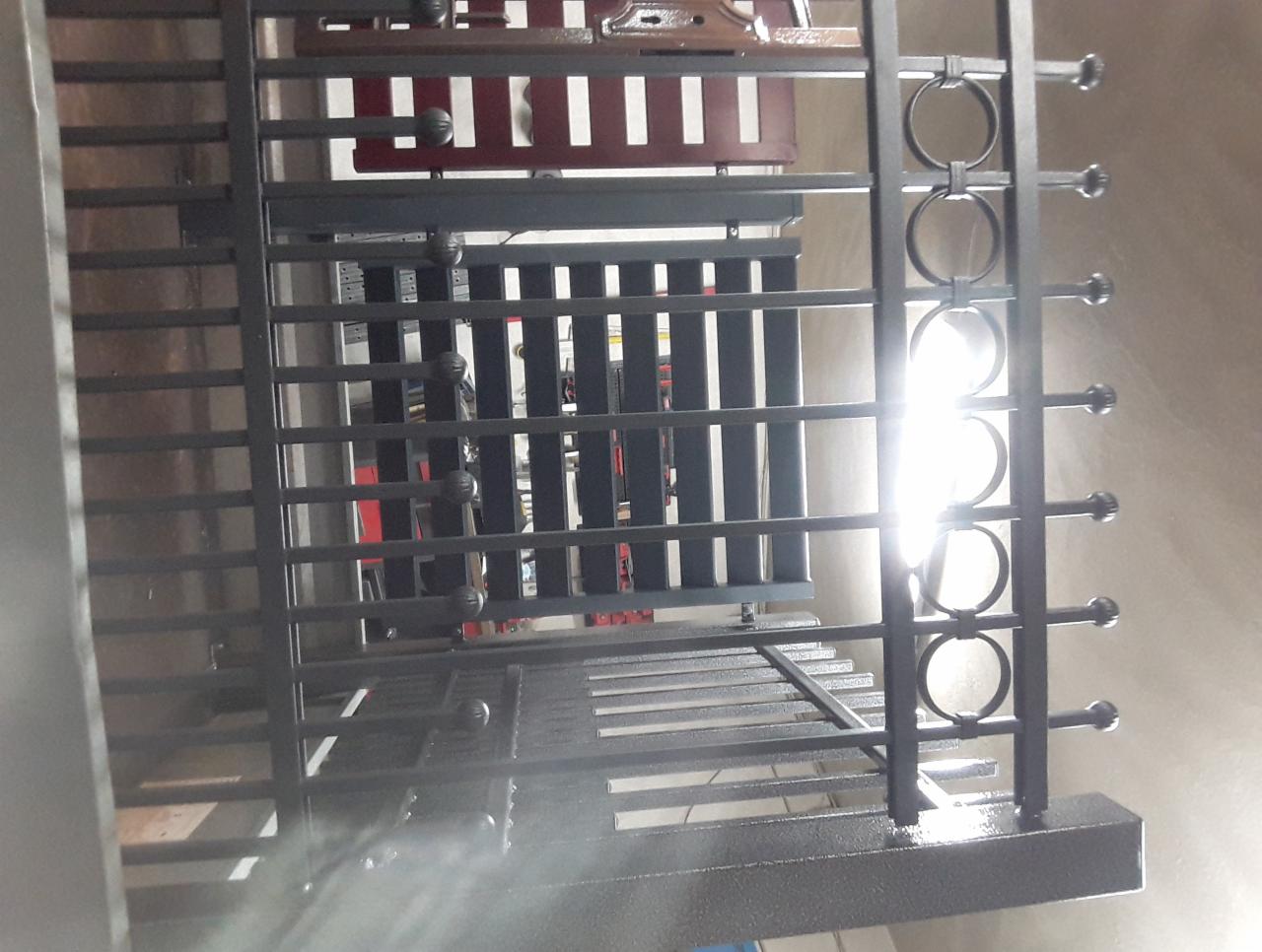 Metalowa konstrukcja z elementami dekoracyjnymi w postaci kół, widok z dołu, oświetlona silnym światłem.