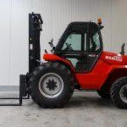 wózki widłowe!! WYNAJEM,SPRZEDAŻ,SERWIS NA TERENIE CAŁEGO KRAJU,ponad 350 wózków na stanie - Czerwony wózek widłowy Manitou z wysuniętym masztem na tle hali magazynowej, widok z boku.