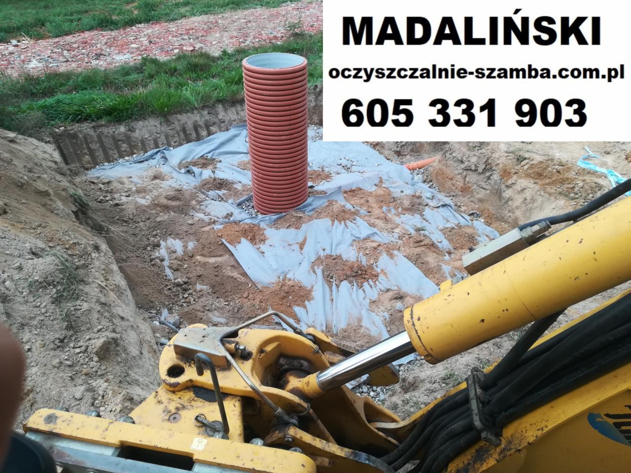 Wykop pod instalację sanitarną z widoczną rurą kanalizacyjną z tworzywa sztucznego, zabezpieczony geowłókniną i częściowo zasypany, w tle ziemia i fragment koparki.