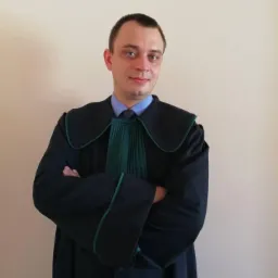 Portret mężczyzny w todze z zielonym żabotem, stojącego na tle jednolitej ściany z założonymi rękami.