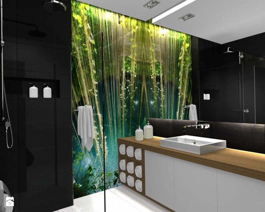 Nowoczesna łazienka z czarnymi płytkami, szklaną ścianą z motywem roślinnym i drewnianym blatem pod umywalką.