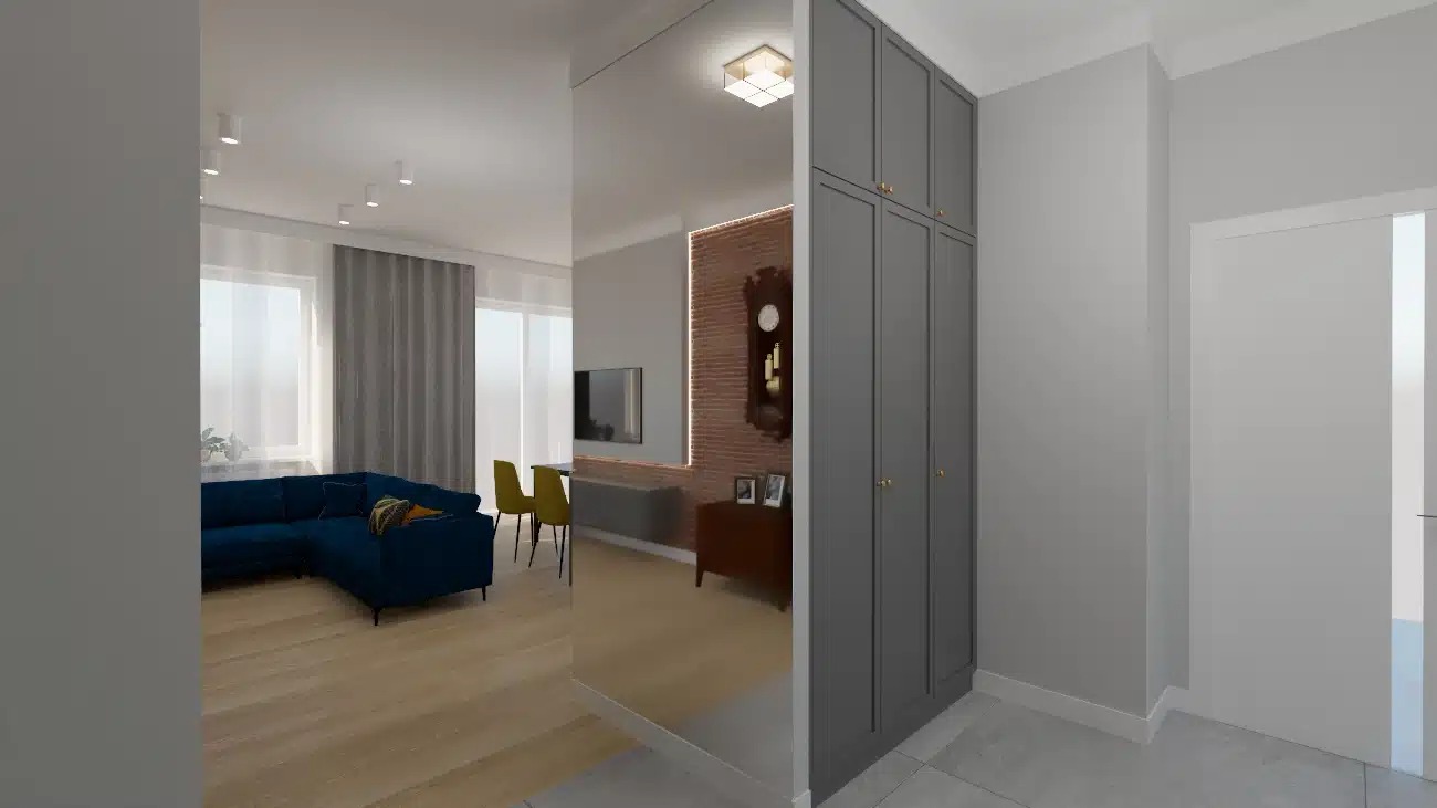 Wnętrze mieszkania z dużym lustrem, odbijającym salon z narożną, granatową sofą i żółtymi krzesłami, obok szara szafa w zabudowie.