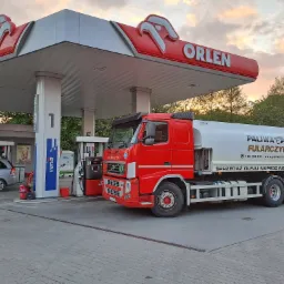 Czerwona cysterna firmy Paliwa Fularczyk na stacji Orlen podczas zachodu słońca, widoczny numer telefonu i adres strony internetowej na cysternie.