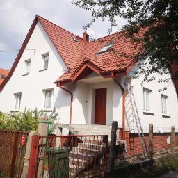 MT2 - Biały dom jednorodzinny z czerwoną dachówką i stolarką okienną, po renowacji elewacji, z rozstawioną drabiną przy ścianie.