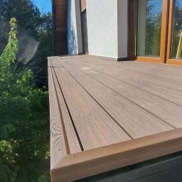 ArtHouse Artur Grzyb - Nowoczesny balkon z kompozytowych desek w Lublińcu, widok z dołu, z widoczną elewacją budynku i roletami zewnętrznymi.