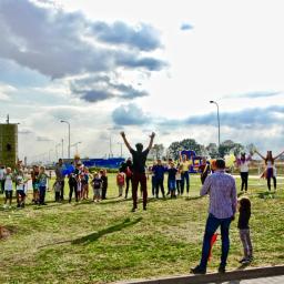 Wojciech Matkowski - Piknik firmowy na trawie z dmuchanym zamkiem w tle, animatorzy w strojach i grupa dzieci uczestniczących w zabawie.