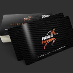 Designers Agencja Multimedialna K. Malinowski - Stos wizytówek z czarnym tłem imitującym włókno węglowe, logo 'Body Design' z sylwetką biegacza w kolorze pomarańczowym i tekstem 'World Class Personal Training', widoczny kod QR.