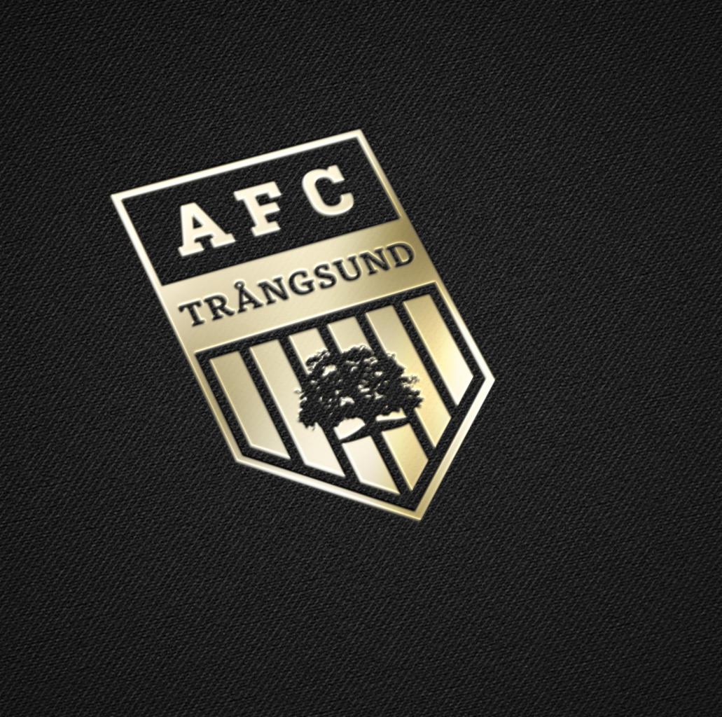 Złoty emblemat z napisem AFC TRANGSUND i stylizowanym drzewem na czarnym teksturowanym tle.