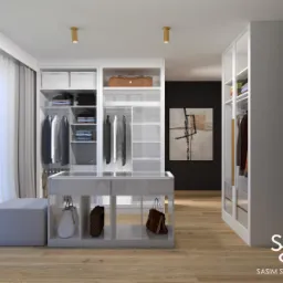 Nowoczesna garderoba w bieli z drewnianą podłogą, wyposażona w półki, wieszaki, szuflady, toaletkę i pufę. Na podłodze torebki, na ścianie obraz w abstrakcyjnym stylu. Widoczne logo SASIM STUDIO.