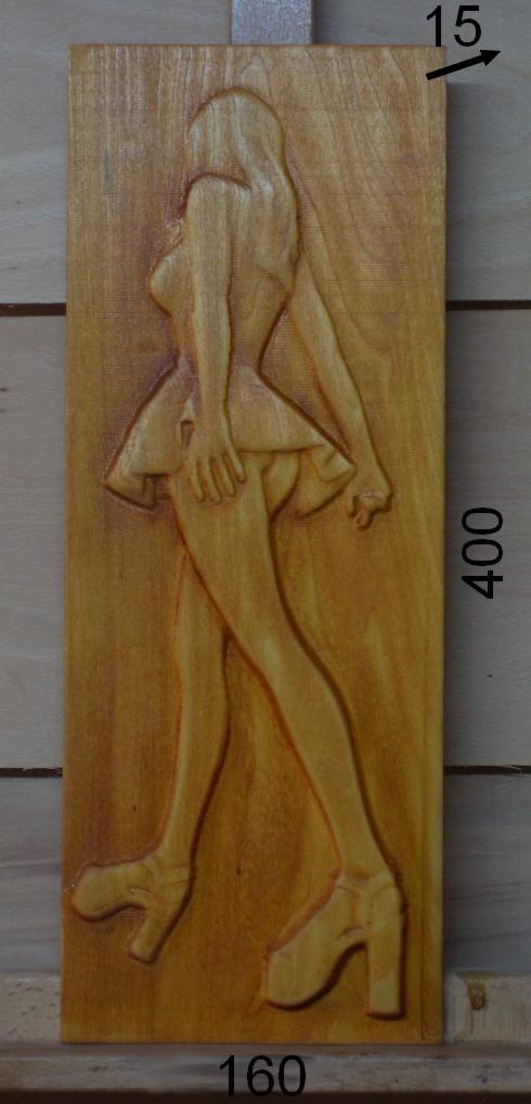 Drewniana płaskorzeźba przedstawiająca sylwetkę kobiety w sukience i na wysokich obcasach, z naniesionymi wymiarami 15x400x160 mm.