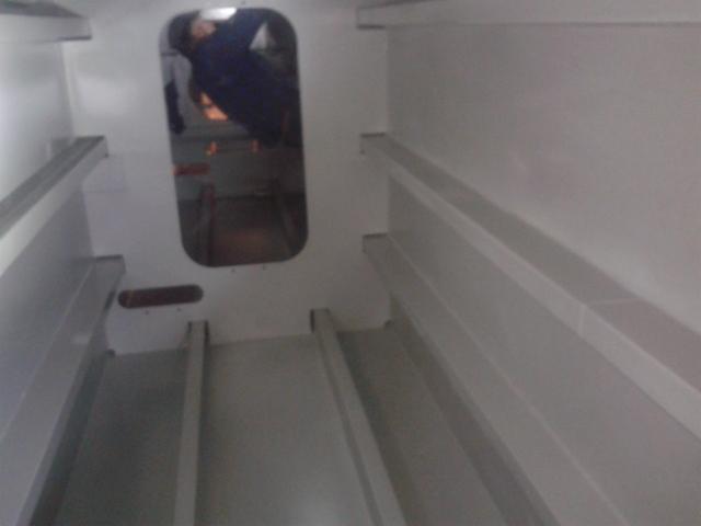 Wnętrze metalowej konstrukcji po obróbce, widoczna osoba w oddali przez otwór, świeżo pomalowane na biało detale w Gdyni.