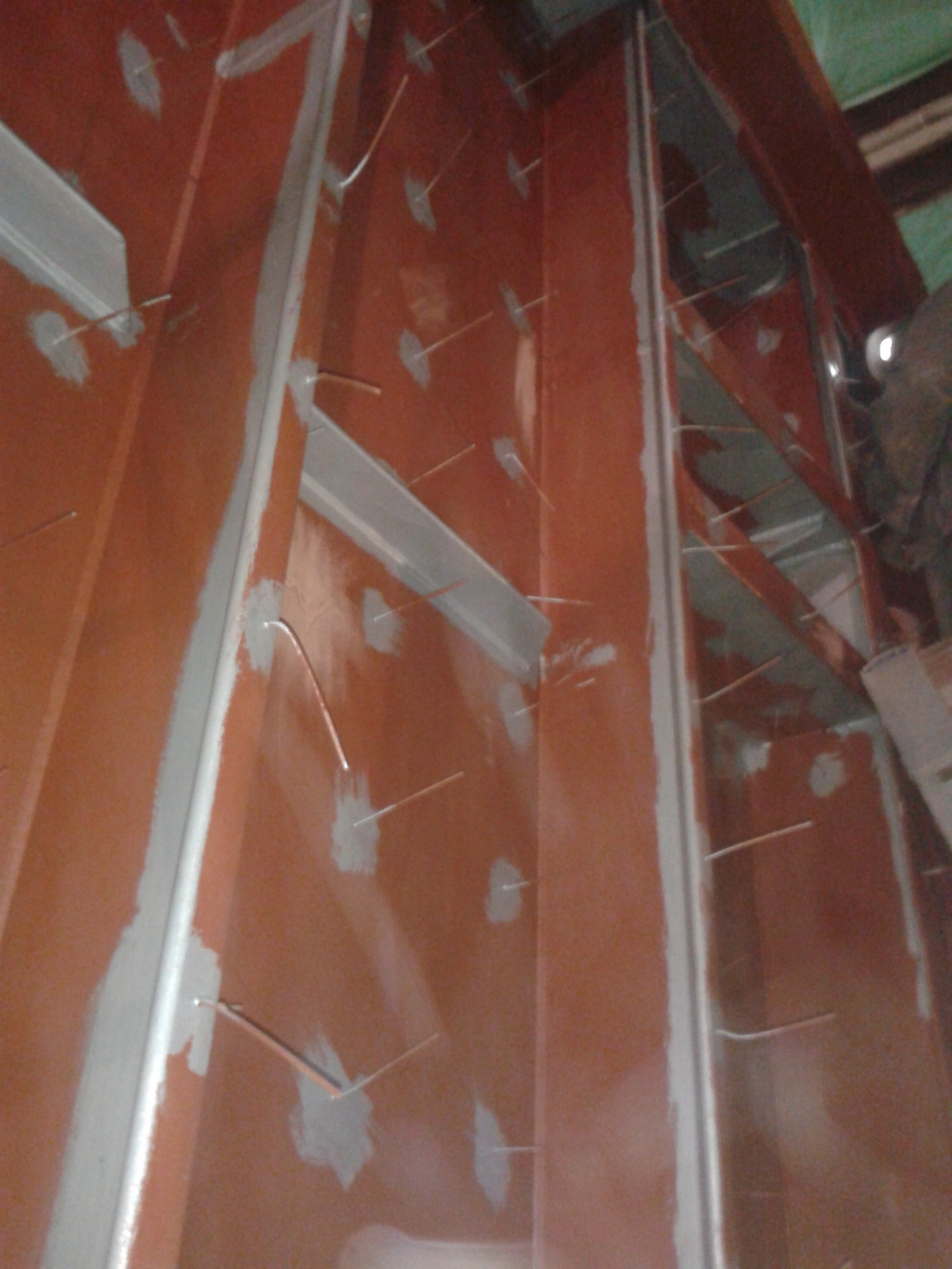 Wnętrze konstrukcji stalowej z przyspawanymi elementami, zabezpieczone szpachlą i farbą antykorozyjną, widoczne wystające druty spawalnicze.