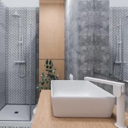 Nowoczesna łazienka z betonowymi ścianami, kabiną prysznicową wyłożoną białą cegiełką, drewnianą szafką z zieloną rośliną i białą, prostokątną umywalką nablatową z minimalistyczną baterią.