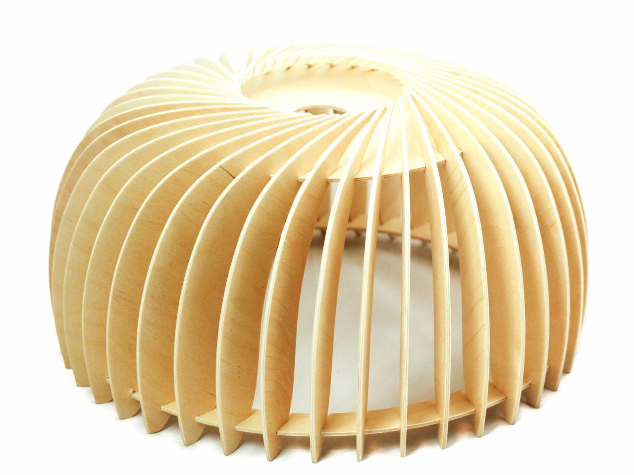 Drewniana ażurowa lampa wisząca w kształcie półkuli, wykonana z jasnej sklejki, z widocznymi warstwami drewna i spiralnym otworem u góry, na białym tle.