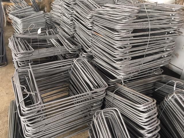 Stos uformowanej stali zbrojeniowej w kształcie prostokątnych strzemion, gotowej do użycia w konstrukcji betonowej.