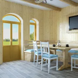 Drewniana jadalnia z oknami łukowymi, telewizorem w drewnianej ramie i drewnianym stołem z białymi krzesłami z niebieskimi poduszkami.