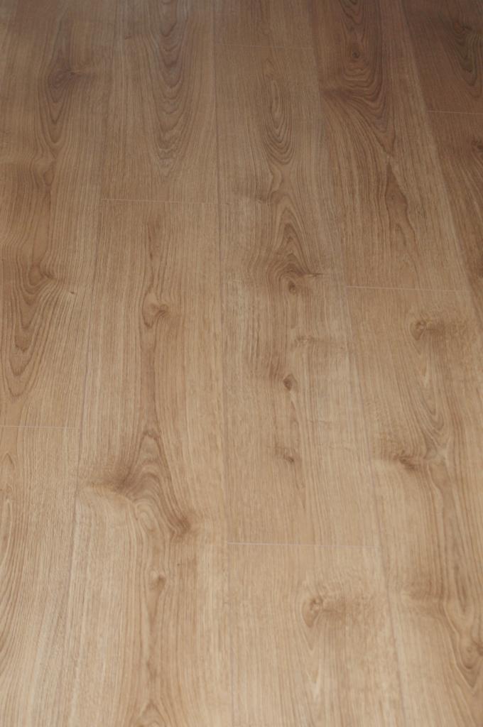 Jasne panele podłogowe z widoczną strukturą drewna ułożone w rzędach, z delikatnym połyskiem i subtelnymi fugami.