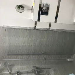 Nowoczesna kabina prysznicowa z szarą mozaiką w romby i chromowaną armaturą, widok z góry.