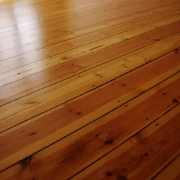 Błyszcząca, świeżo polakierowana podłoga z desek sosnowych ułożonych diagonalnie, z widocznymi słojami drewna i refleksami światła.