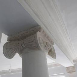 Krzycki - Renowacje - Detal kolumny z kapitelem jońskim w trakcie prac wykończeniowych, surowy tynk na kolumnie i listwach sufitowych, widoczne ślady szpachlowania.