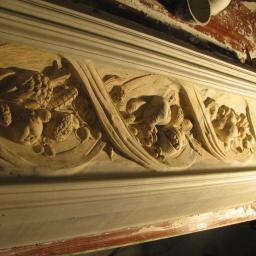 Krzycki - Renowacje - Dekoracyjny gzyms z motywami owoców i roślin, wykonany z gipsu lub stiuku, w trakcie renowacji, widoczne narzędzia i ślady pracy.