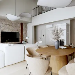 Wnętrze salonu z jadalnią: biała sofa, drewniany stół z krzesłami, spiralne schody, ściana z kamienia, nowoczesne lampy. Aranżacja w jasnych, neutralnych barwach.