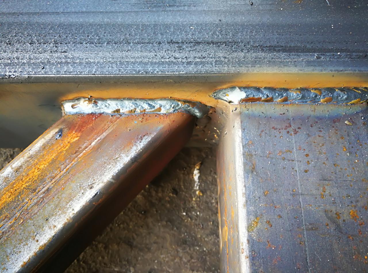Spoina łącząca stalowe elementy konstrukcji, widoczne ślady rdzy i niedoskonałości spoiny.