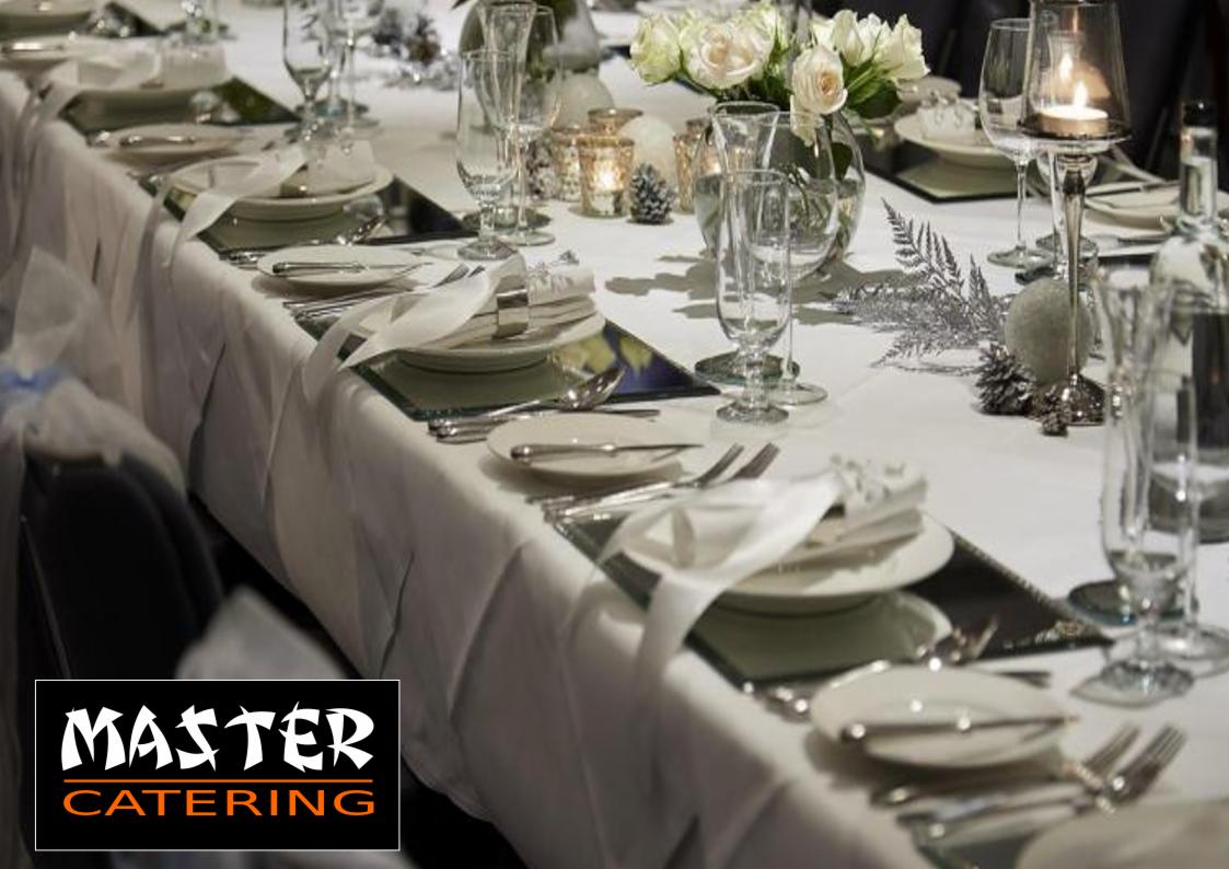 Elegancko nakryty stół z białym obrusem, srebrnymi sztućcami i szklanymi naczyniami, dekorowany białymi różami i świecami, z logo firmy na pierwszym planie.