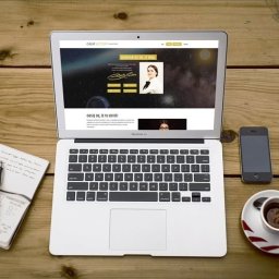 Usługi informatyczne Krystian Widźgowski - Laptop z otwartą stroną internetową Calm Victory na drewnianym biurku obok notatnika z zapiskami, smartfona i filiżanki kawy espresso.