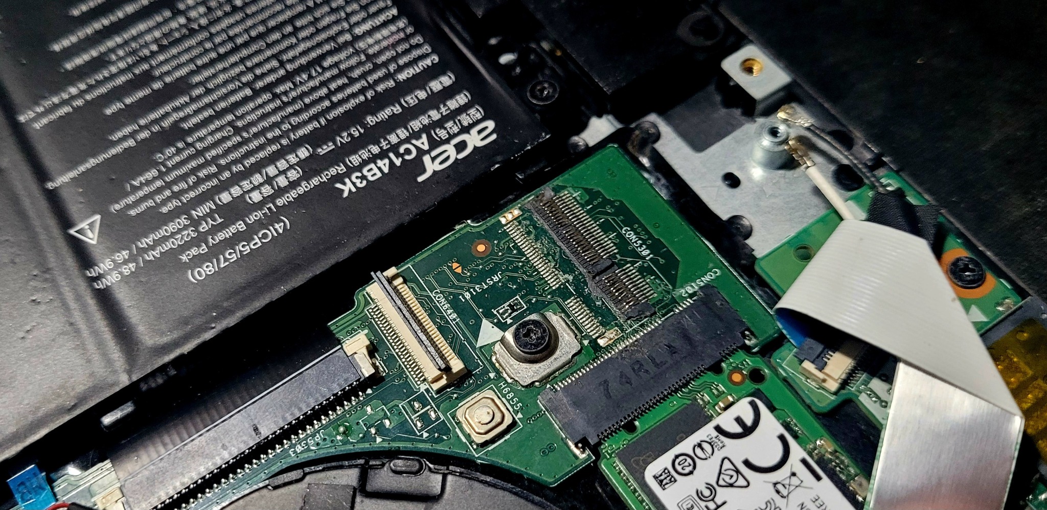 Wnętrze laptopa Acer z widoczną płytą główną, baterią i elementami złącz. Detaliczne ujęcie elektroniki podczas naprawy lub modernizacji.