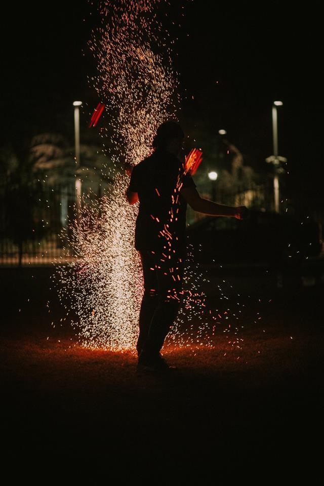 Nocny pokaz fireshow w Siewierzu: artysta żongluje płonącymi rekwizytami, tworząc deszcz iskier na ciemnym tle.