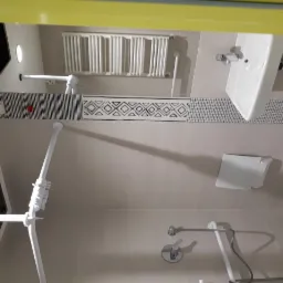 Wykończona łazienka z zamontowaną armaturą, grzejnikiem drabinkowym, umywalką i uchwytami dla niepełnosprawnych, wykończona płytkami z dekoracyjnym pasem.