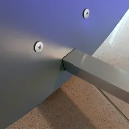 Szczegół mocowania metalowej nogi do blatu stołu za pomocą śrub w Krosno, widoczny fragment podłogi.