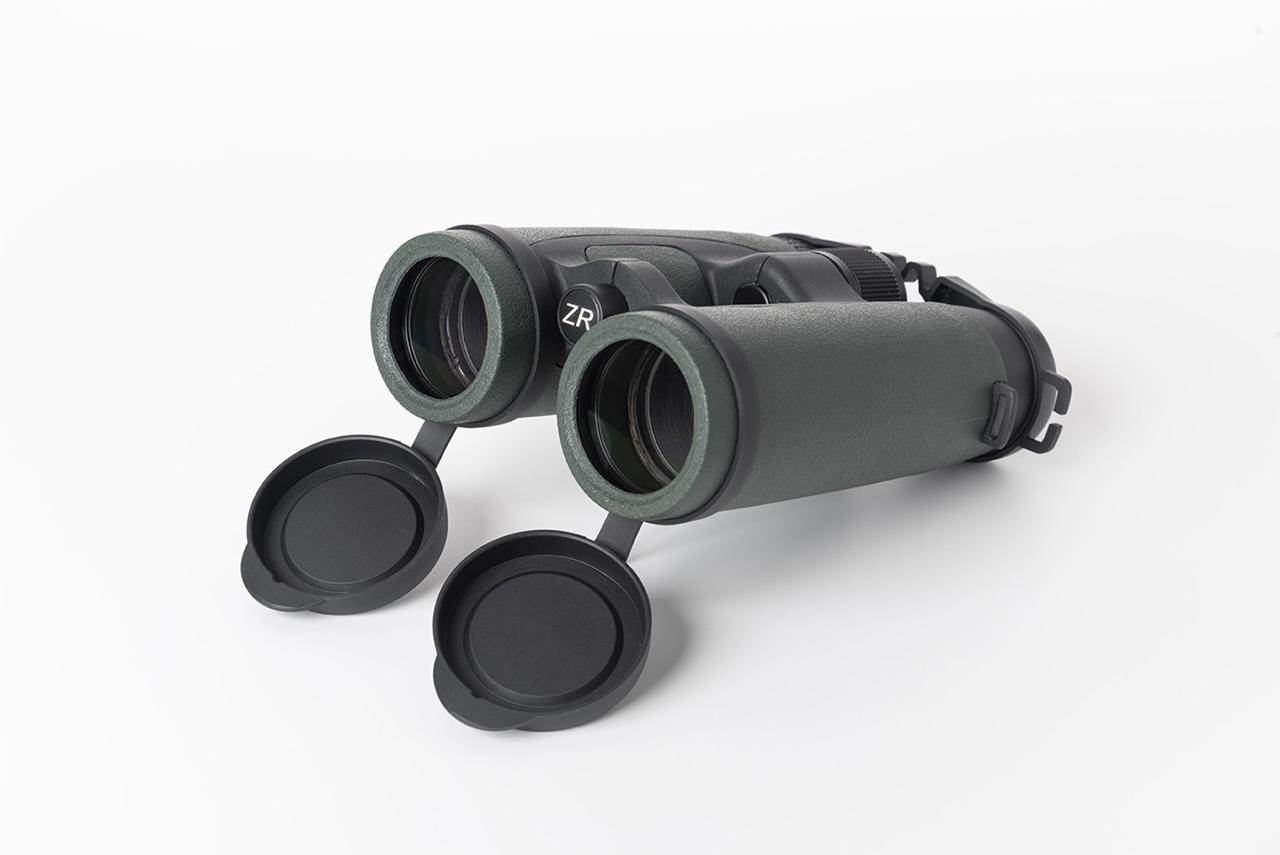 Szare lornetki ZR z otwartymi osłonami obiektywów, leżące na białym tle