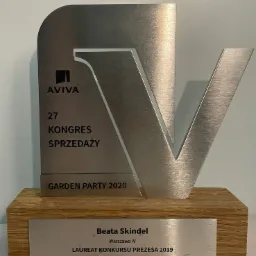 Srebrna statuetka Aviva z okazji 27 Kongresu Sprzedaży Garden Party 2020, na drewnianej podstawie z tabliczką 'Beata Skindel, Warszawa IV, Laureat Konkursu Prezesa 2019'.
