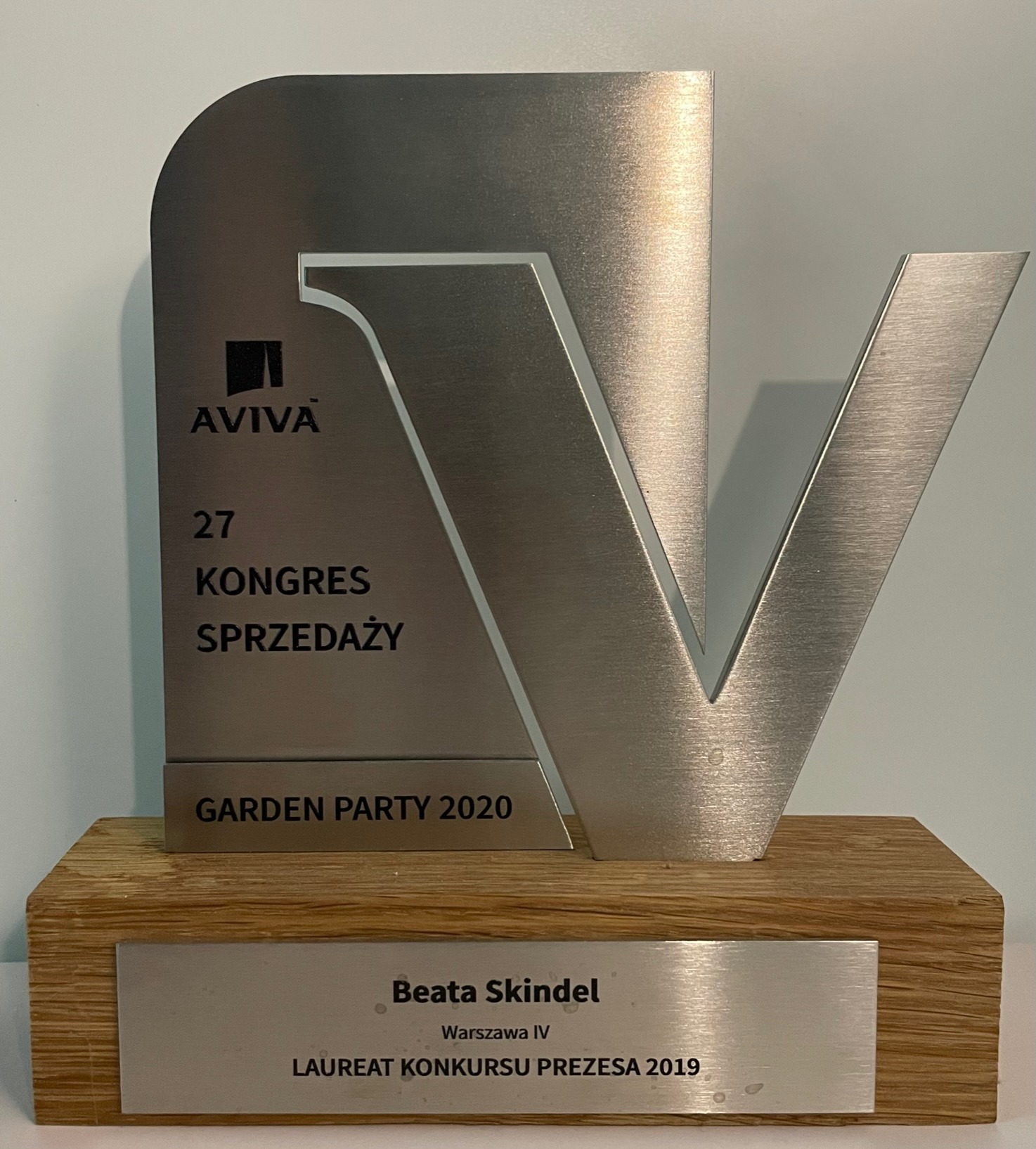 Srebrna statuetka Aviva z okazji 27 Kongresu Sprzedaży Garden Party 2020, na drewnianej podstawie z tabliczką 'Beata Skindel, Warszawa IV, Laureat Konkursu Prezesa 2019'.