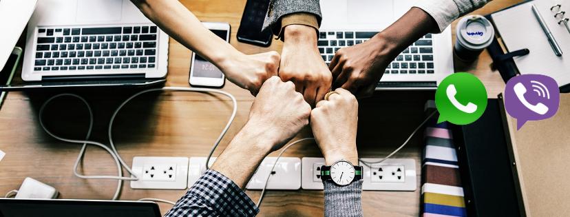 Zespół pięciu osób z różnym kolorem skóry uderza pięściami w geście solidarności nad biurkiem z laptopami, telefonem i przedłużaczami