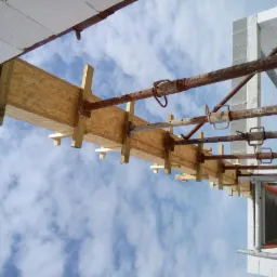 Szczegółowe ujęcie szalunku stropu na budynku z betonu komórkowego, widok z dołu na niebieskie niebo z chmurami.