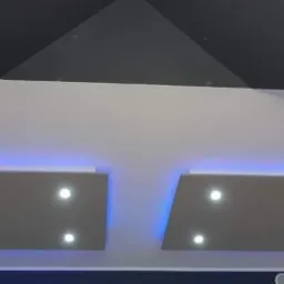 Nowoczesny sufit podwieszany z płyt kartonowo-gipsowych z oświetleniem punktowym i niebieską listwą LED.