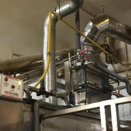 Wymiennik ciepła z podłączonymi rurami, widoczny panel sterowania z napisem Eurotechnika i diodą sygnalizującą pracę pompy.