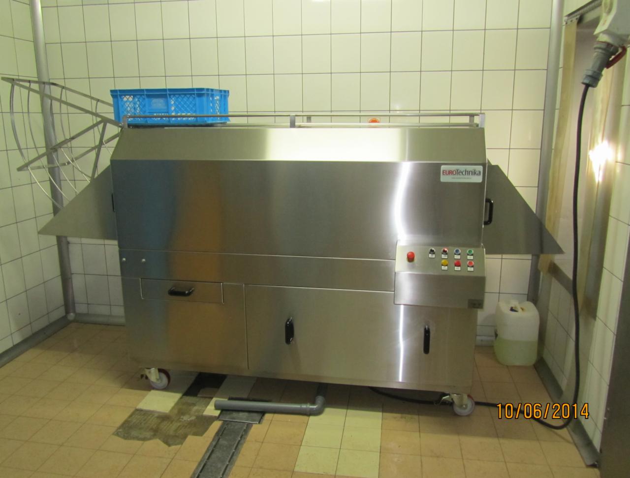 Profesjonalna, przemysłowa zmywarka do naczyń marki EuroTechnika ze stali nierdzewnej, z niebieskim koszem na górze, stojąca w pomieszczeniu z wykafelkowanymi ścianami i podłogą.