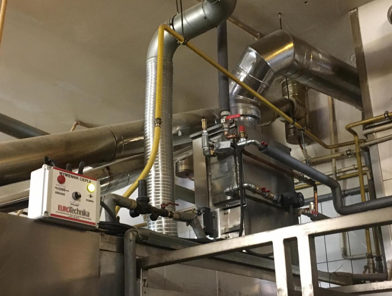 Wymiennik ciepła z podłączonymi rurami, widoczny panel sterowania z napisem Eurotechnika i diodą sygnalizującą pracę pompy.