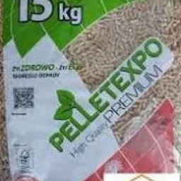 Przezroczysty worek 15 kg wypełniony jasnymi, drobnymi granulkami opału, z zielono-białą etykietą Pellet Expo Premium i naklejką Oferteo Najlepsi 2023 w prawym dolnym rogu.